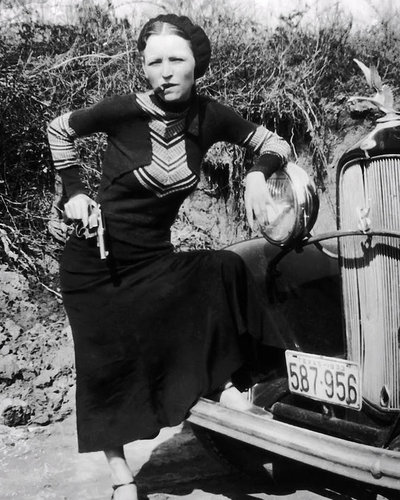 Bonnie Parker posing with a cigar and gun. 